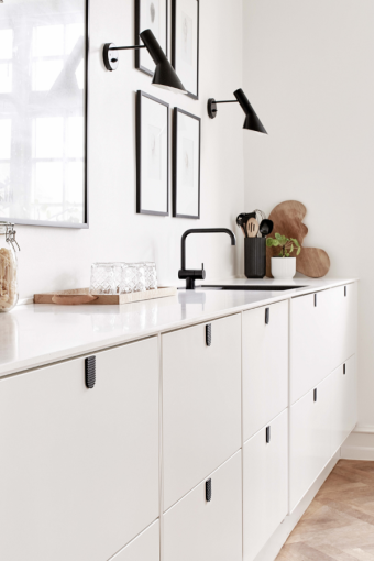 Primer plano de muebles blancos minimalistas con tiradores negros y  detalles de armarios de cocina